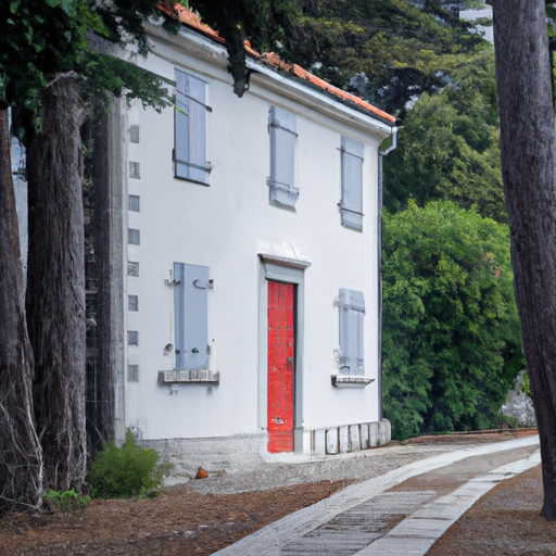 A white house with grey shutters a stone walkway and a red door surrounded by tall trees