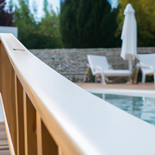 A wooden deck with a white railing overlooking a pool in the background